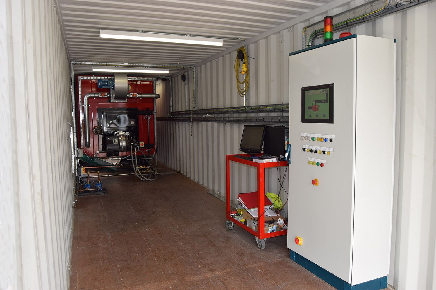 Inside the lower container: the machine on the left, and the control cabinet with its touch screen on the right.